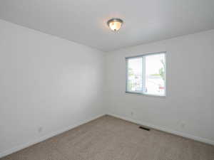 Carpeted spare room featuring baseboards