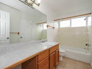 Bathroom with vanity, shower / washtub combination, toilet, and tile patterned floors