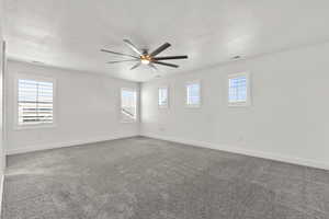 Carpeted spare room with baseboards, ceiling fan, and a textured ceiling