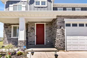 Entrance to property with board and batten siding, a garage, and stone siding