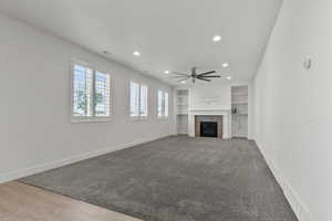 Unfurnished living room featuring recessed lighting, ceiling fan, built in features, baseboards, and a tiled fireplace