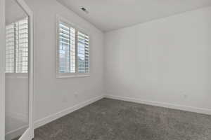 Empty room featuring dark carpet and baseboards