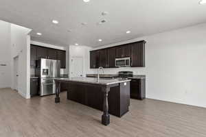 Kitchen featuring appliances with stainless steel finishes, baseboards, a sink, dark brown cabinetry, and recessed lighting