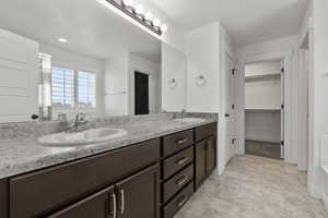 Bathroom with double vanity and a walk in closet