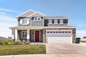 View of front of home featuring board and batten siding, driveway, a garage, and covered porch