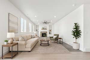 Living area featuring built in shelves, a ceiling fan, a tiled fireplace, recessed lighting, and wood finished floors