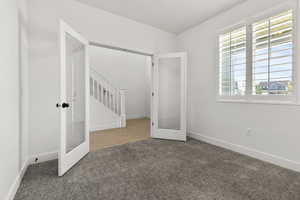 Unfurnished bedroom featuring carpet, french doors, and baseboards