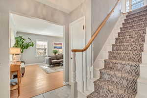 Staircase featuring baseboards, wood finished floors, and crown molding