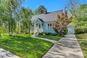 View of front of house with a front yard, a shingled roof, a garage, and a chimney
