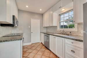 Kitchen featuring stainless steel appliances, a sink, light tile patterned flooring, white cabinets, and recessed lighting