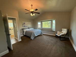 Bedroom featuring baseboards, dark carpet, lofted ceiling, and ceiling fan