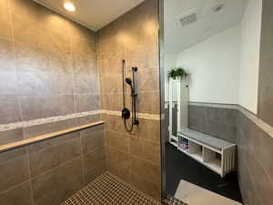 Full bath with tiled shower, tile walls, wainscoting, and recessed lighting