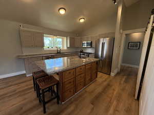 Kitchen featuring high end appliances, a sink, tasteful backsplash, a breakfast bar, and vaulted ceiling