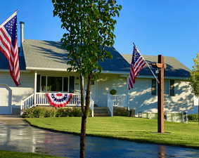 View of front of home with a porch, a shingled roof, a front yard, and driveway