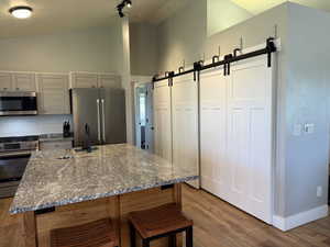 Kitchen with stainless steel appliances, a barn door, a sink, backsplash, and light wood-style floors