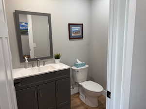 Bathroom featuring toilet, vanity, wood finished floors, and baseboards