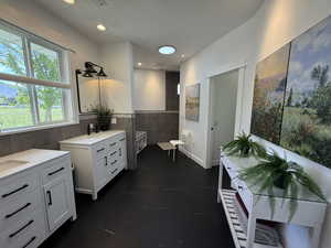 Bathroom with tile walls, two vanities, and recessed lighting