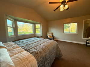Bedroom with vaulted ceiling, baseboards, carpet flooring, and a ceiling fan