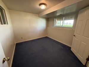 Spare room with dark carpet and baseboards