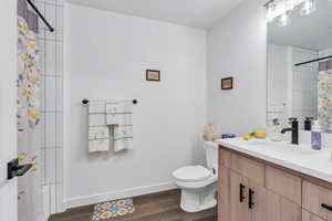 Bathroom with toilet, wood finished floors, and a vanity