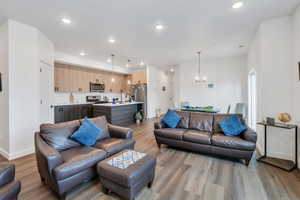 Living room with light wood-style floors, recessed lighting, and a chandelier