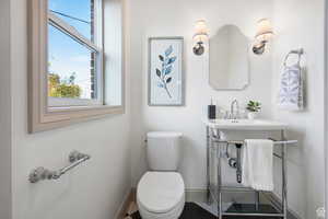 Bathroom with baseboards, plenty of natural light, and toilet