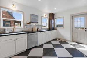 Kitchen featuring dishwasher, a sink, dark countertops, recessed lighting, and white cabinetry