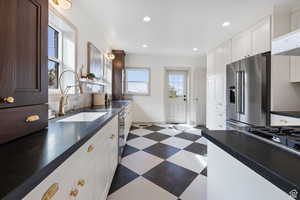 Kitchen with appliances with stainless steel finishes, a sink, dark floors, dark countertops, and recessed lighting