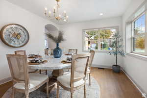 Dining area with wood finished floors, a chandelier, healthy amount of natural light, and recessed lighting