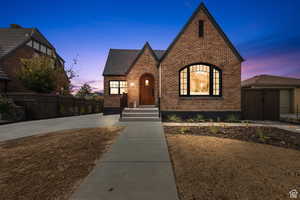 Tudor house with brick siding, fence, and roof with shingles