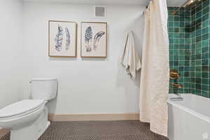 Full bath featuring baseboards, toilet, shower / bath combo with shower curtain, and tile patterned floors