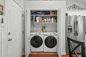 Laundry area with washer and dryer and wood finished floors