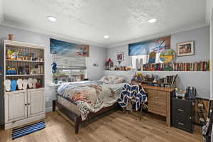 Bedroom with ornamental molding, a textured ceiling, wood finished floors, and recessed lighting