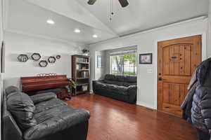 Living room with vaulted ceiling, a ceiling fan, crown molding, dark wood-type flooring, and recessed lighting