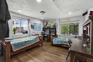 Bedroom featuring a textured ceiling, wood finished floors, multiple windows, and recessed lighting