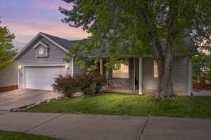 View of front of property with concrete driveway, roof with shingles, a front lawn, and an attached garage