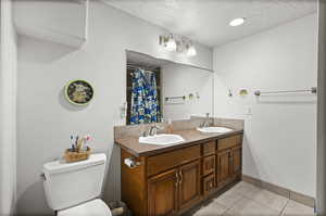 Full bath with a textured ceiling, tile patterned flooring, toilet, baseboards, and a shower with curtain