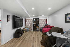 Living area with light wood-style flooring, recessed lighting, and baseboards