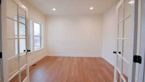 Spare room featuring french doors, light wood finished floors, baseboards, and recessed lighting