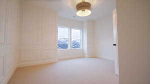Empty room featuring light colored carpet and a decorative wall