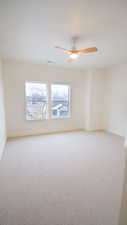 Empty room with light colored carpet, baseboards, and a ceiling fan
