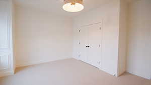 Unfurnished bedroom featuring light colored carpet, a closet, and baseboards
