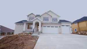 View of front of home featuring driveway, a garage, and stone siding
