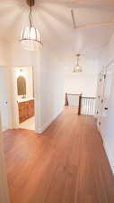 Hallway with wood finished floors, baseboards, and an upstairs landing