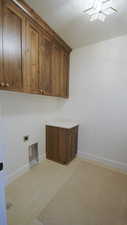 Laundry room with electric dryer hookup, cabinet space, and baseboards