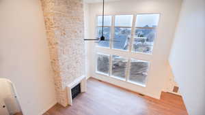 Unfurnished living room featuring wood finished floors, plenty of natural light, a glass covered fireplace, and a ceiling fan