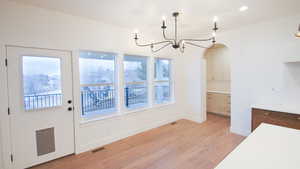 Unfurnished dining area featuring light wood-type flooring, baseboards, plenty of natural light, a chandelier, and recessed lighting