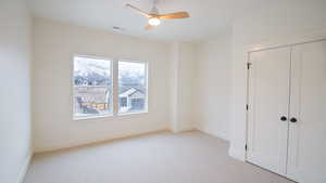 Unfurnished bedroom with carpet, baseboards, a closet, and a ceiling fan