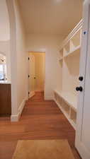 Mudroom with arched walkways, wood finished floors, and baseboards