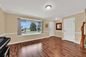 Entrance foyer featuring wood finished floors, ornamental molding, a textured ceiling, and baseboards